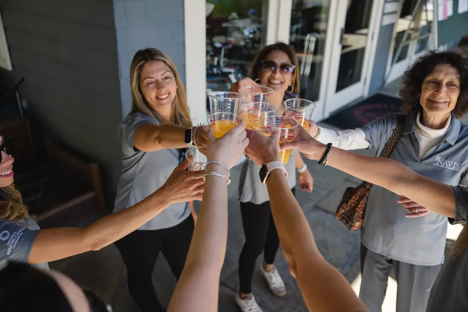 Volunteers in matching grey polos raising mimosa glasses in a toast