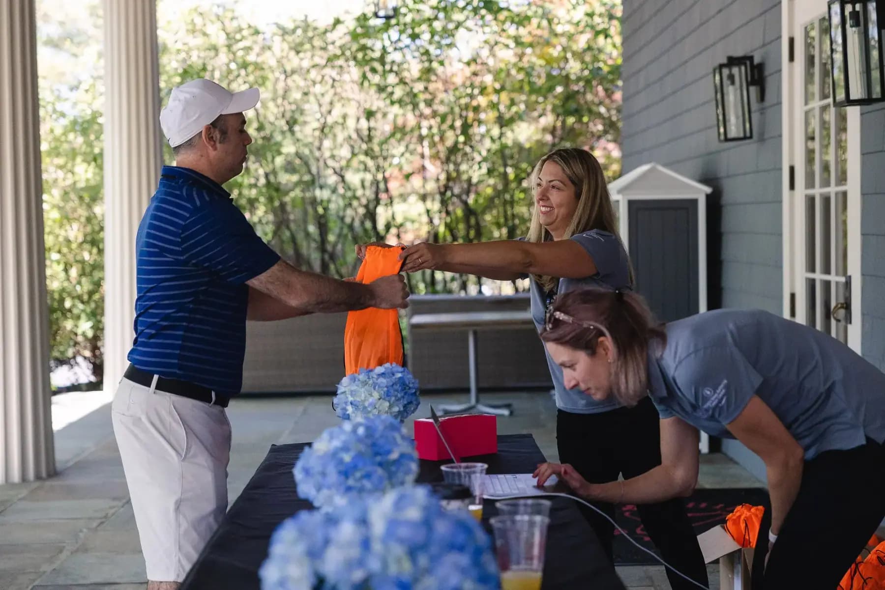 Golfer in a navy polo collecting a gift bag from volunteers at the registration table