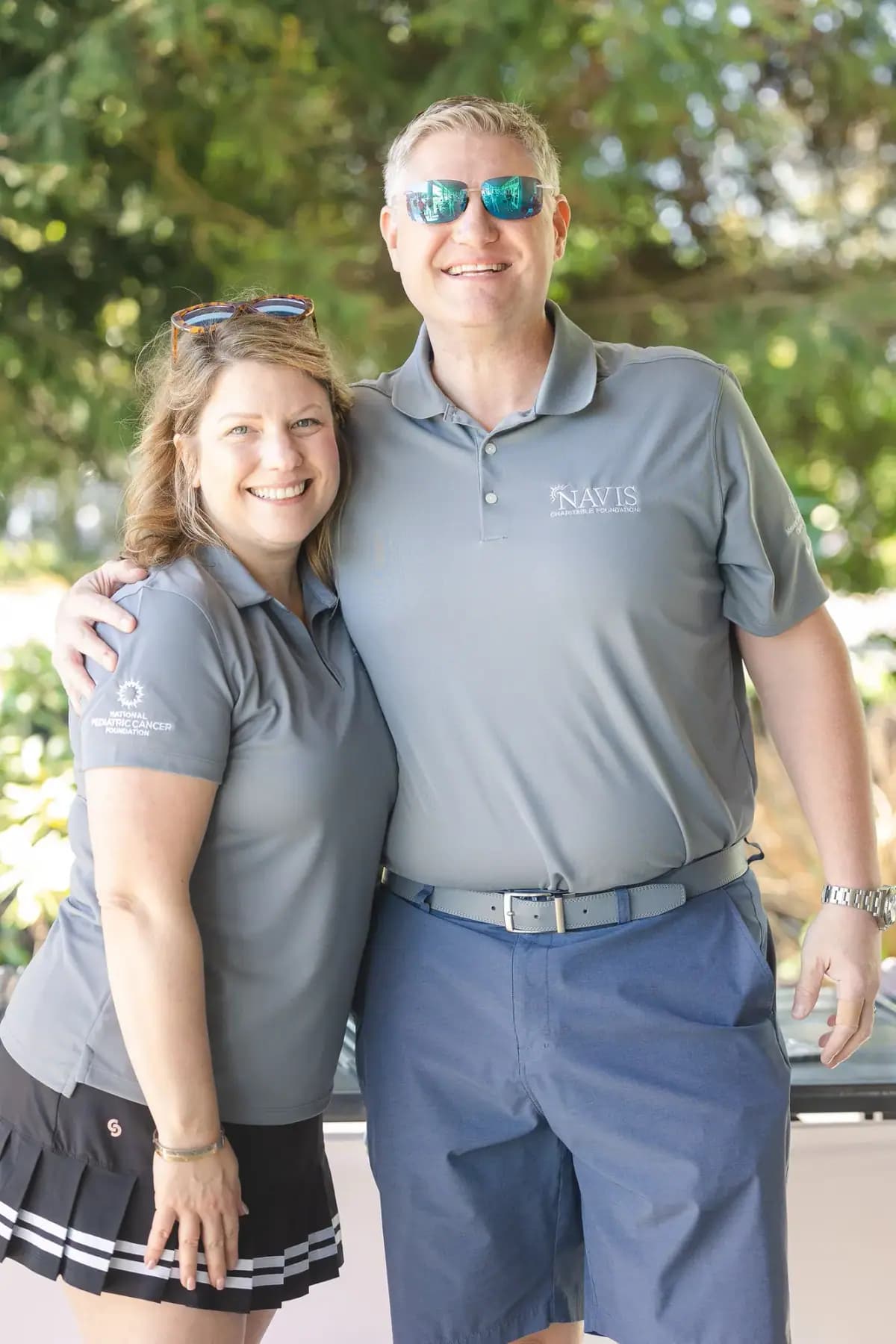 Smiling couple in grey Navis polos posing together outdoors