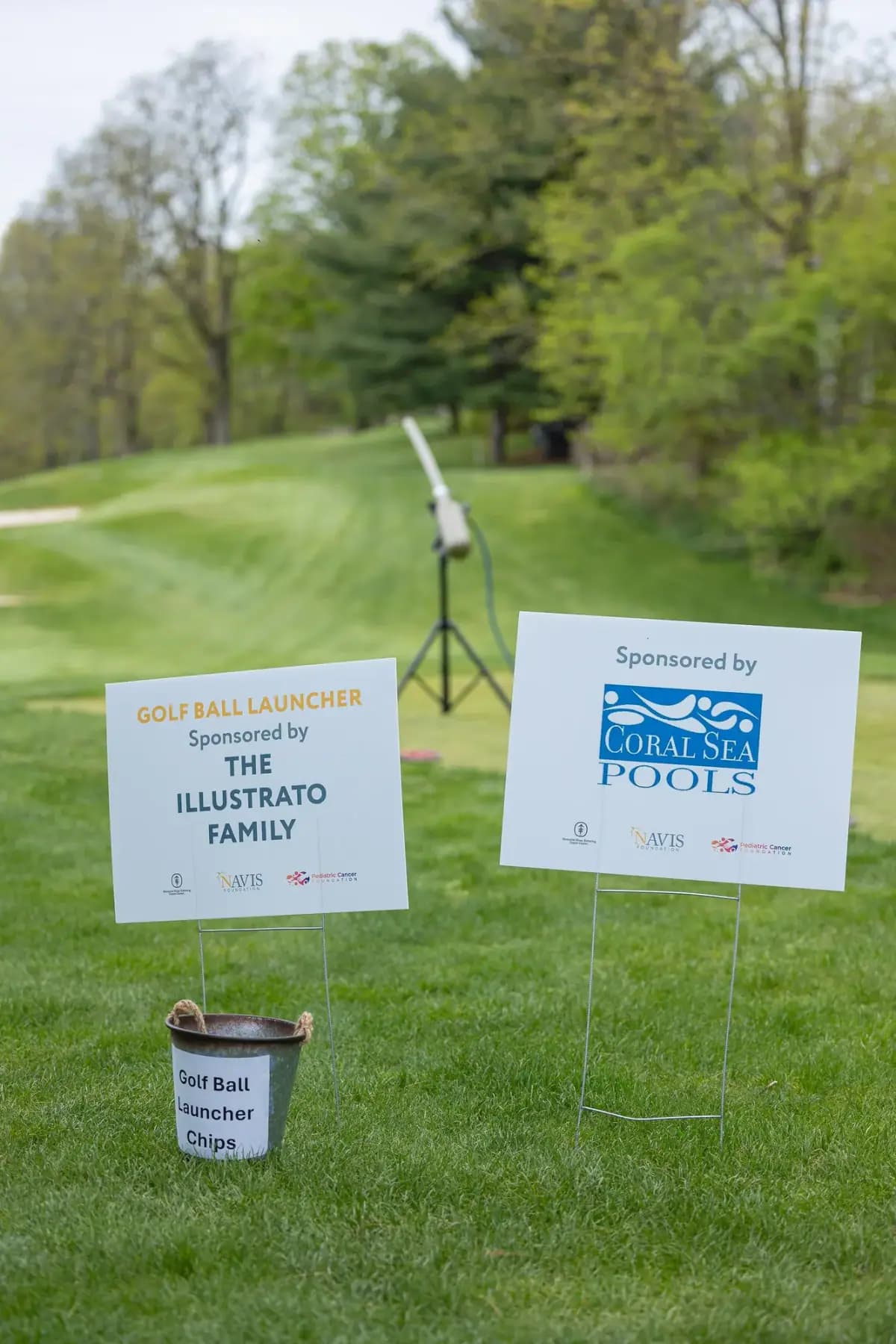 Golf ball launcher and hole sponsor signs for The Illustrato Family and Coral Sea Pools