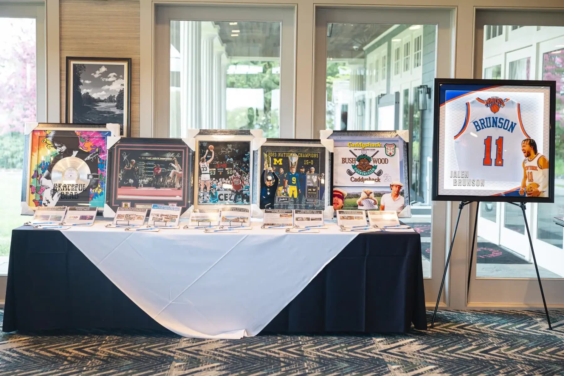 Silent auction table with framed sports memorabilia and art