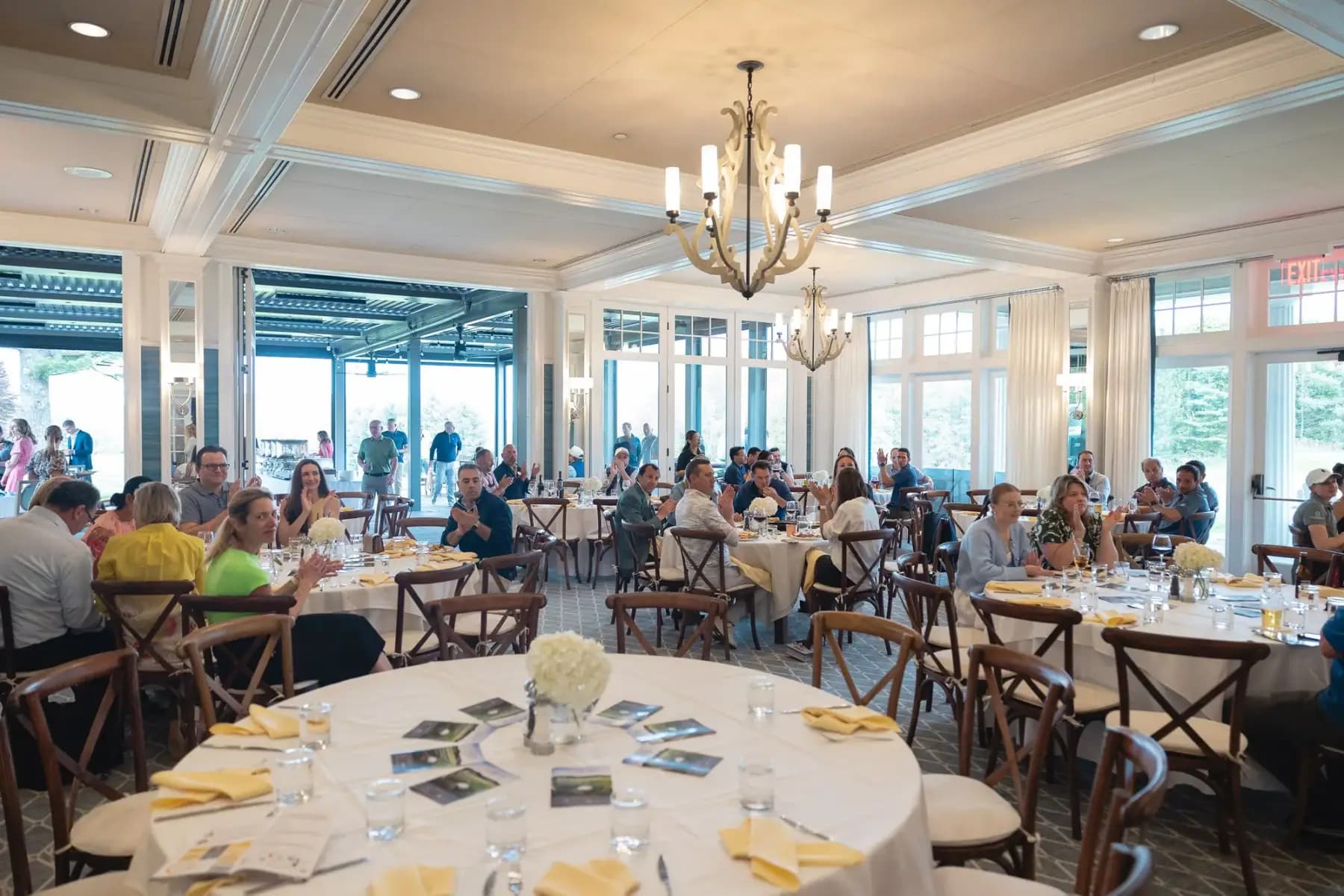 Clubhouse dining room with round tables and guests seated for dinner