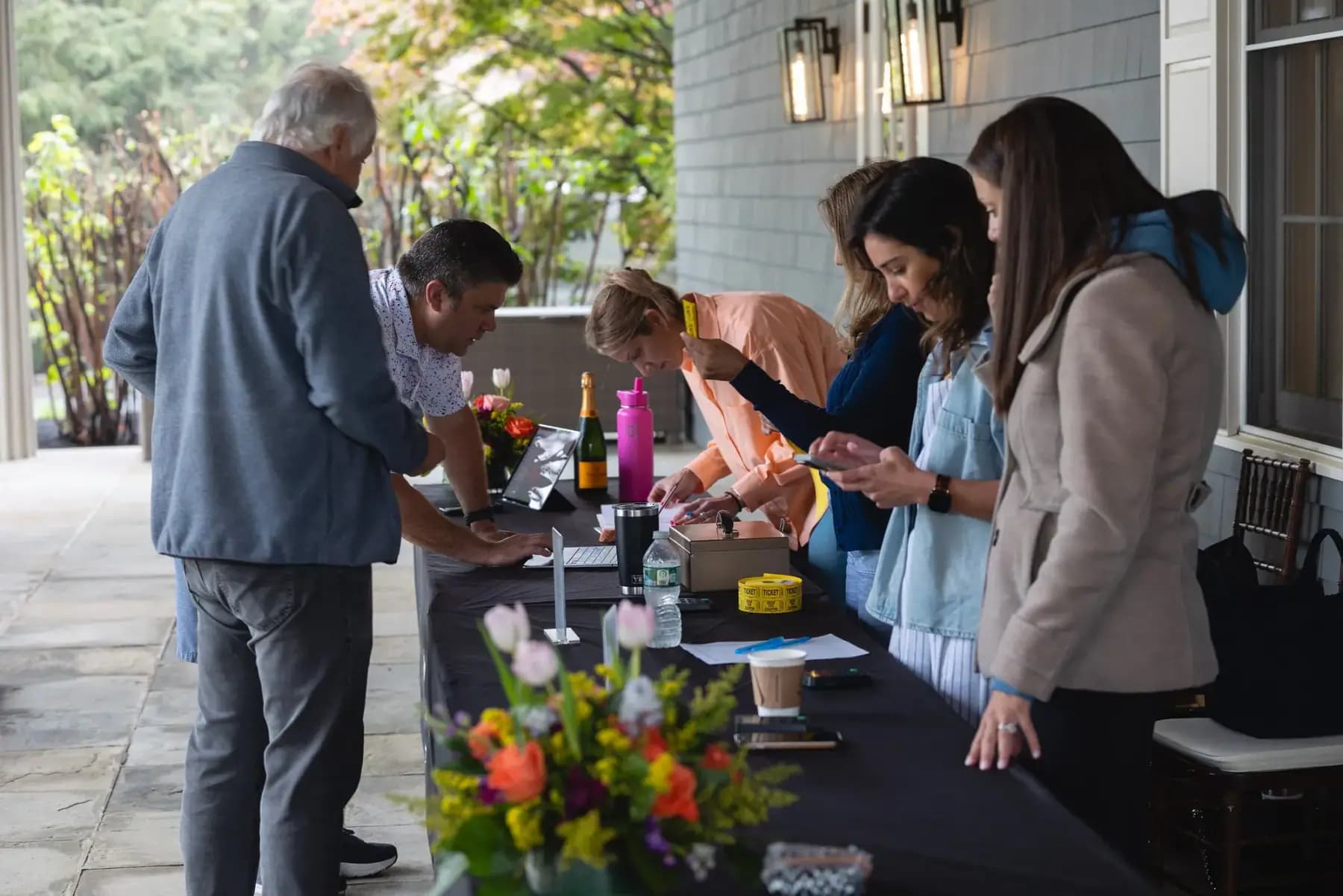 Guests checking in at a flower-decorated registration table on the porch