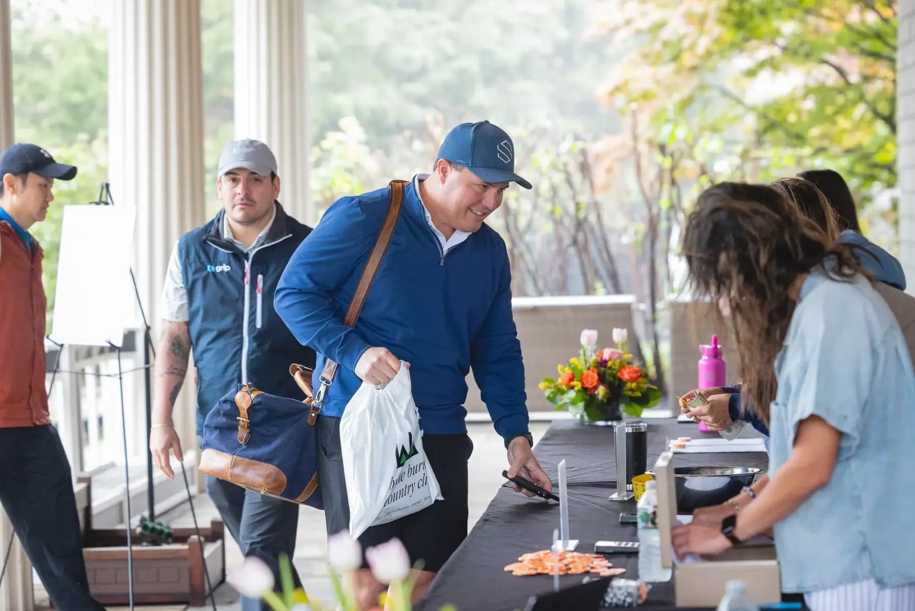 Golfers in rain jackets collecting gift bags at registration