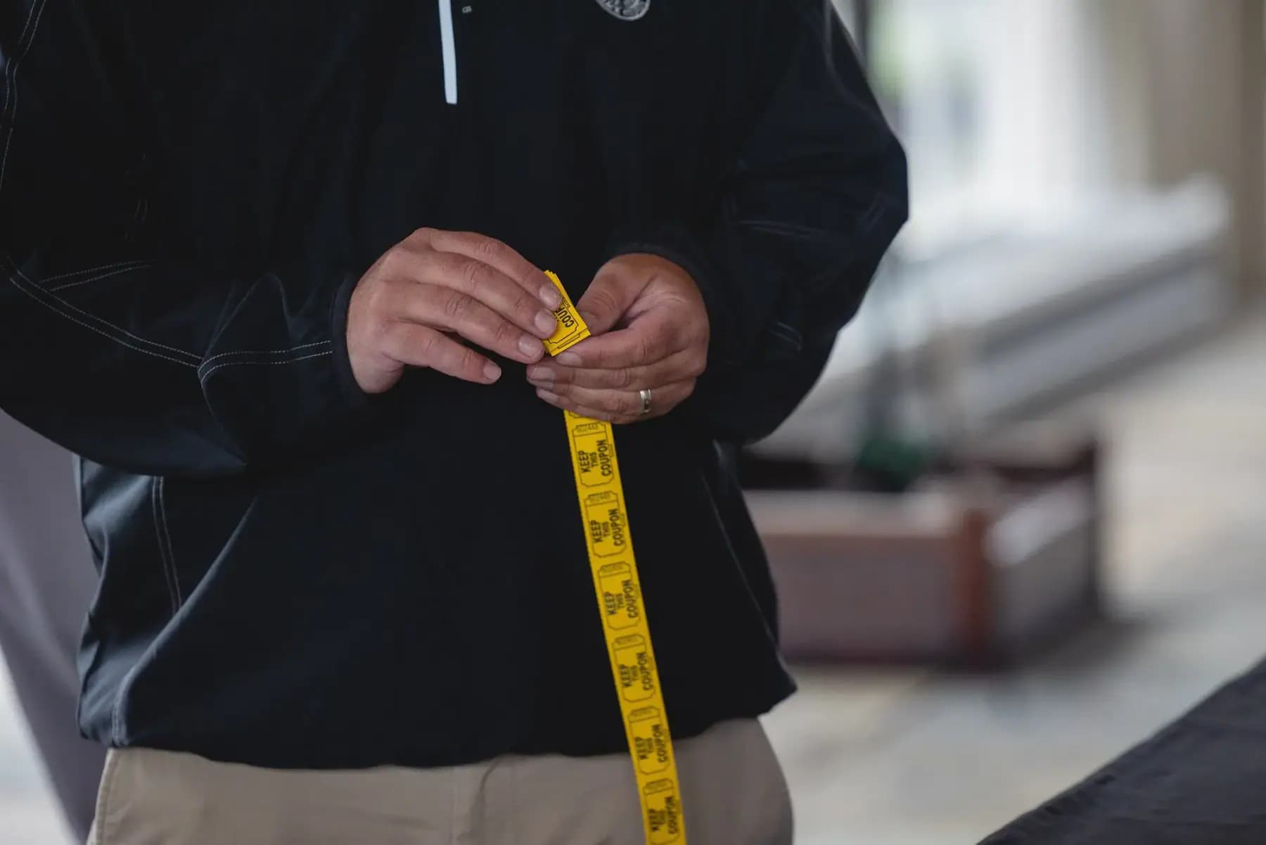 Close-up of a man's hands holding a yellow measuring tape