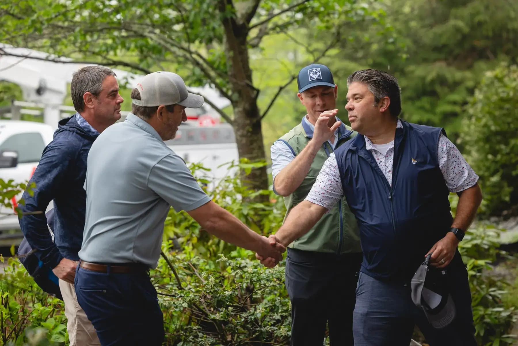 Golfers shaking hands and talking near the parking area