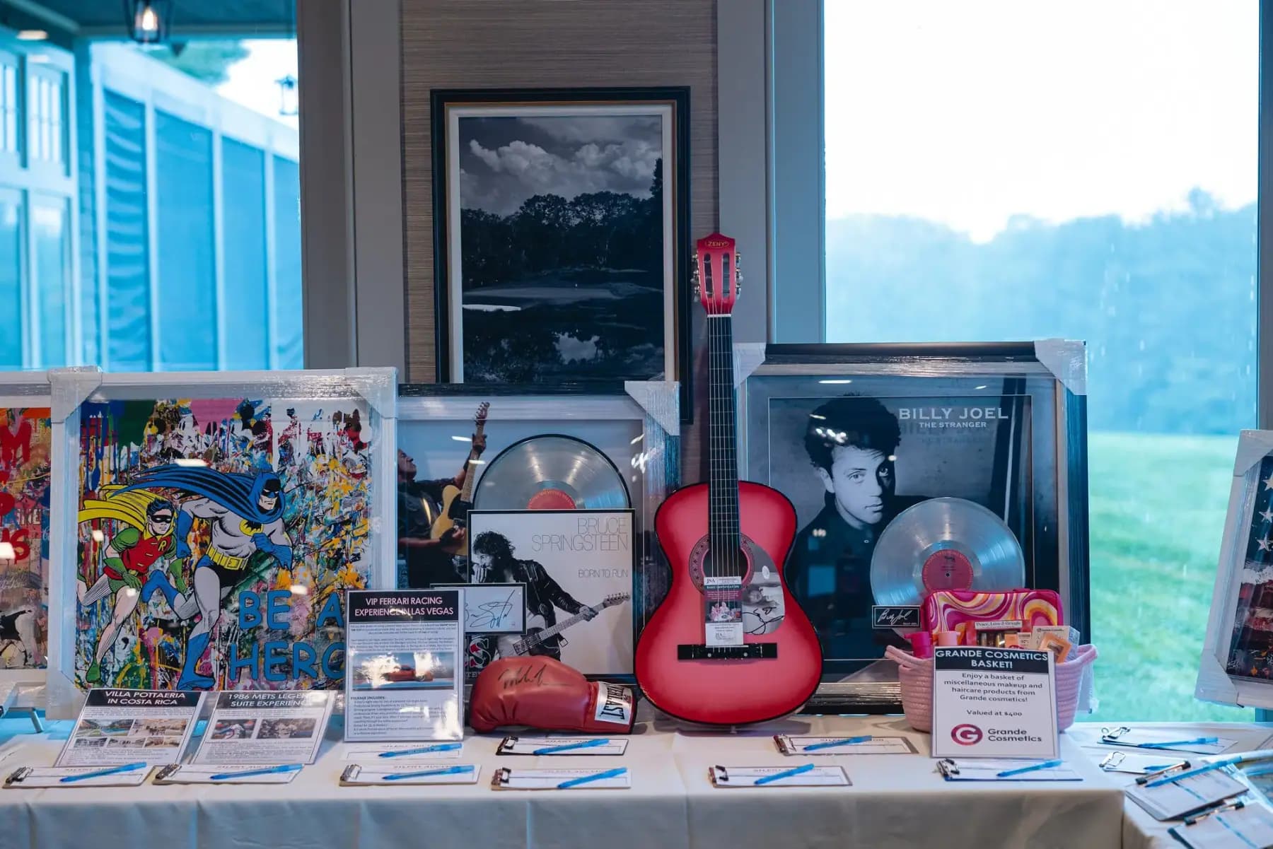 Silent auction table with an autographed guitar and framed memorabilia