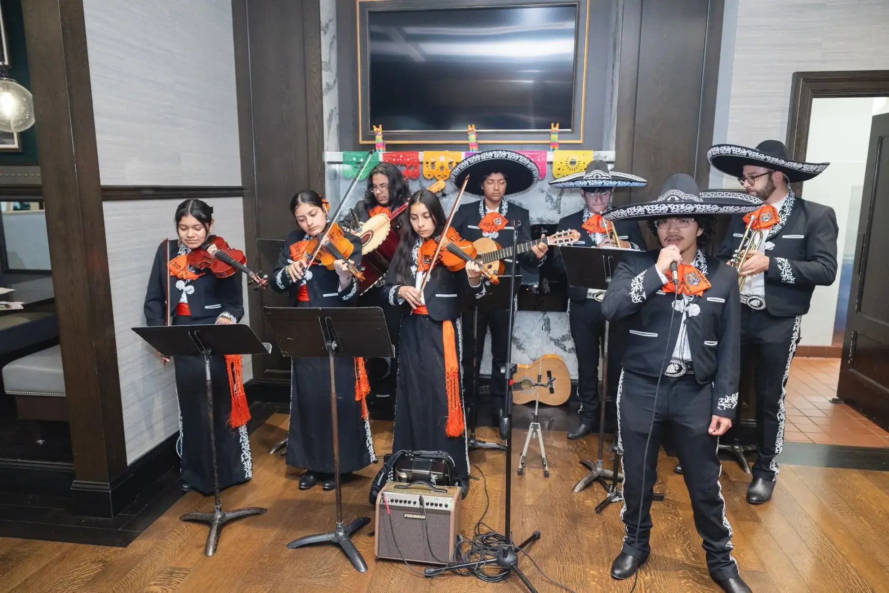 Mariachi band in sombreros performing indoors with violins and guitars
