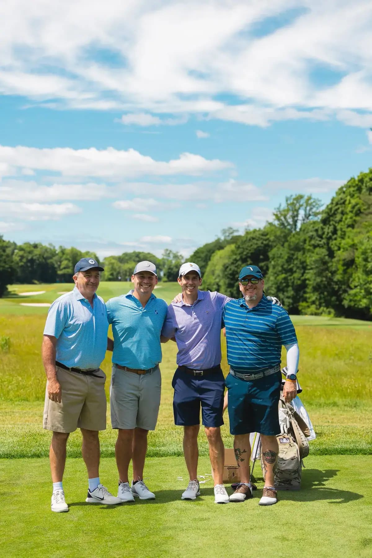 Four golfers in blue polos posing on a fairway