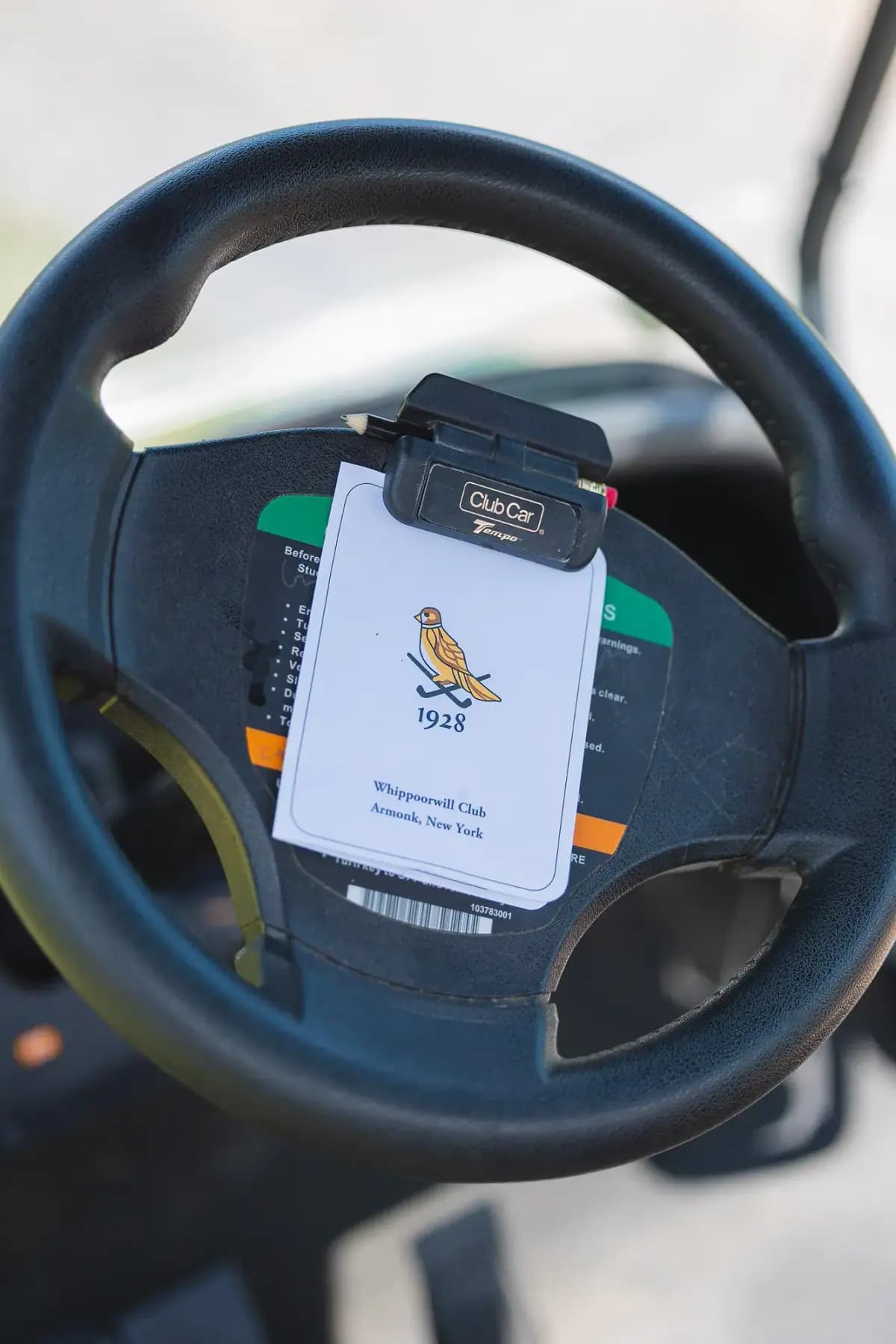 Close-up of a golf cart steering wheel with a course scorecard clip