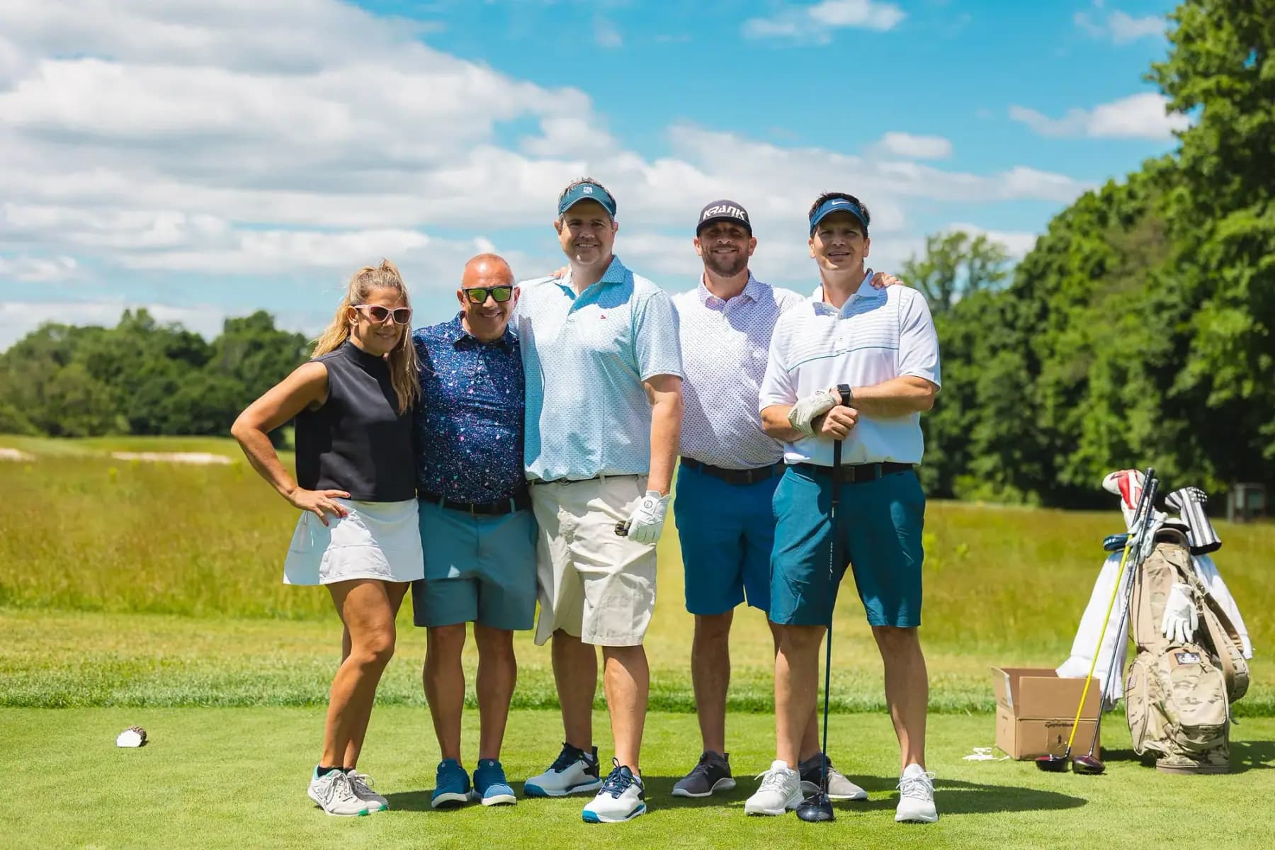 Group of men and women golfers posing on a tee box