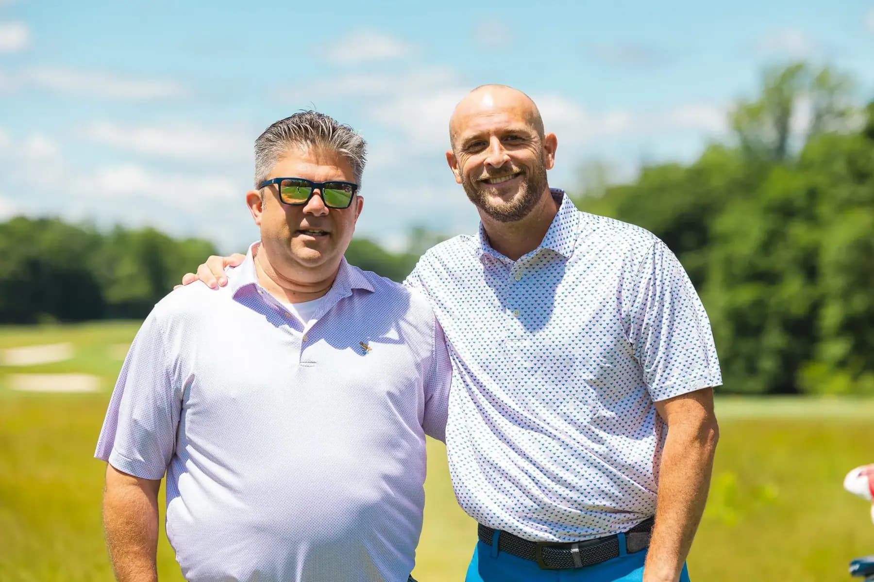 Two men posing together on the course on a sunny day