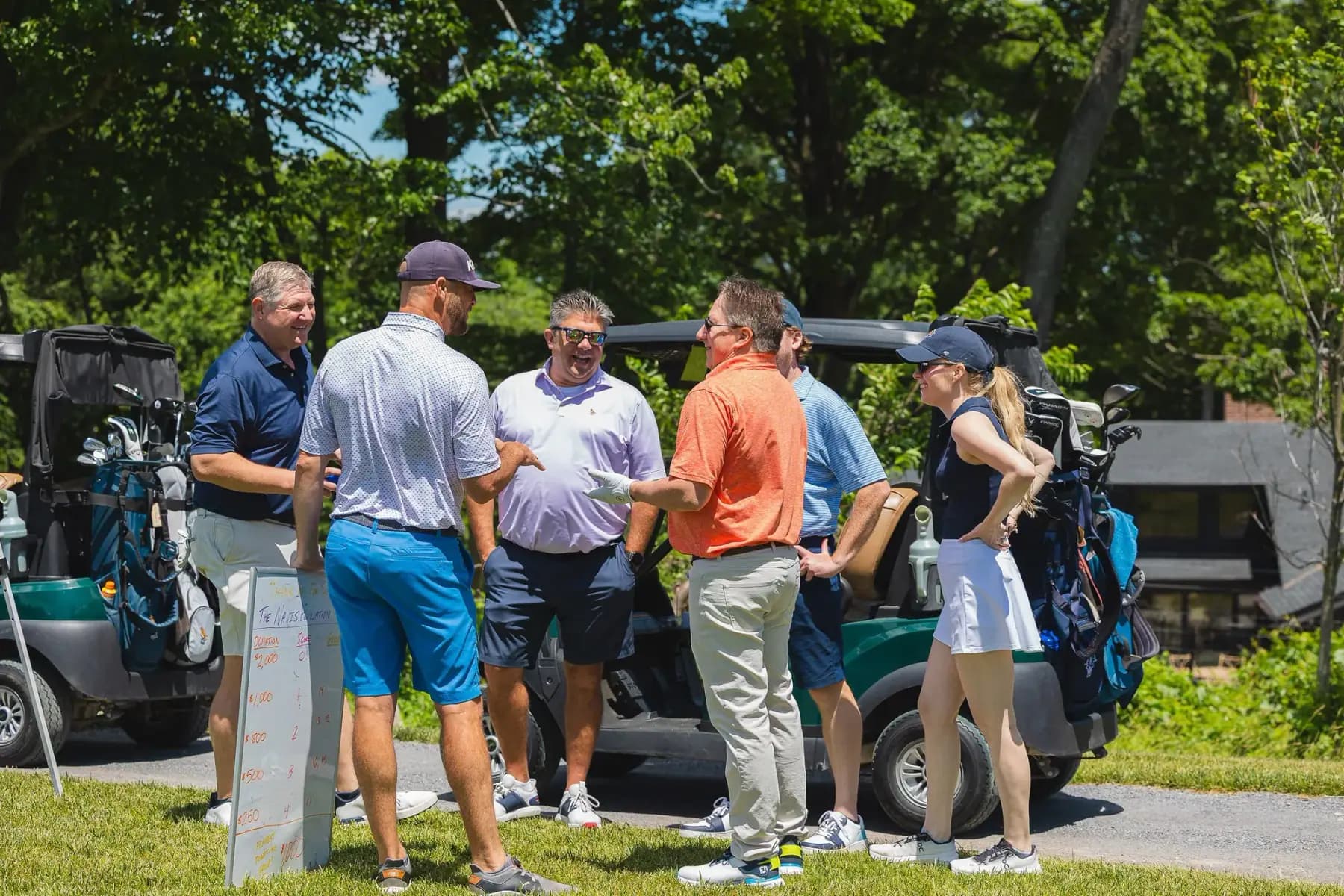 Golfers chatting beside carts at the bag drop