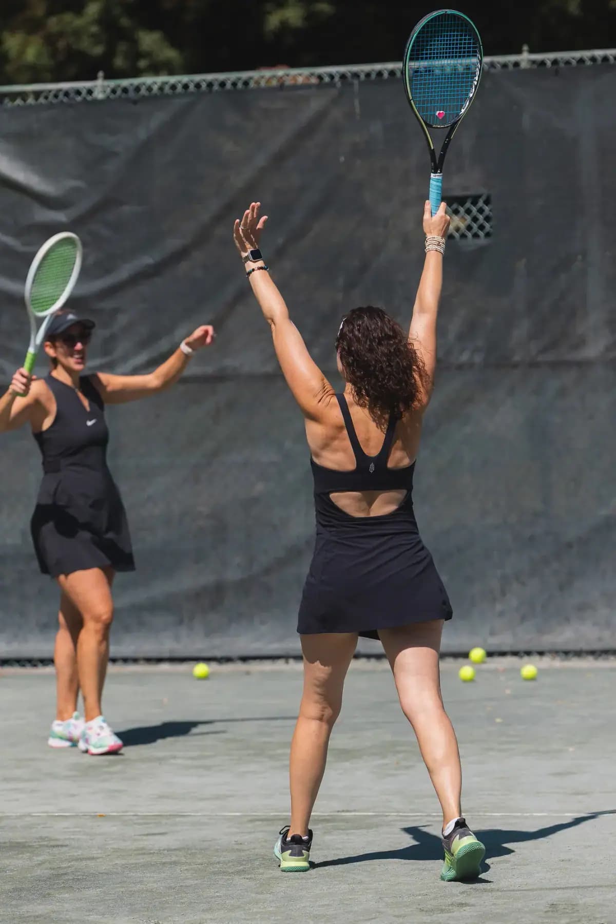 Two women celebrating with rackets raised on court