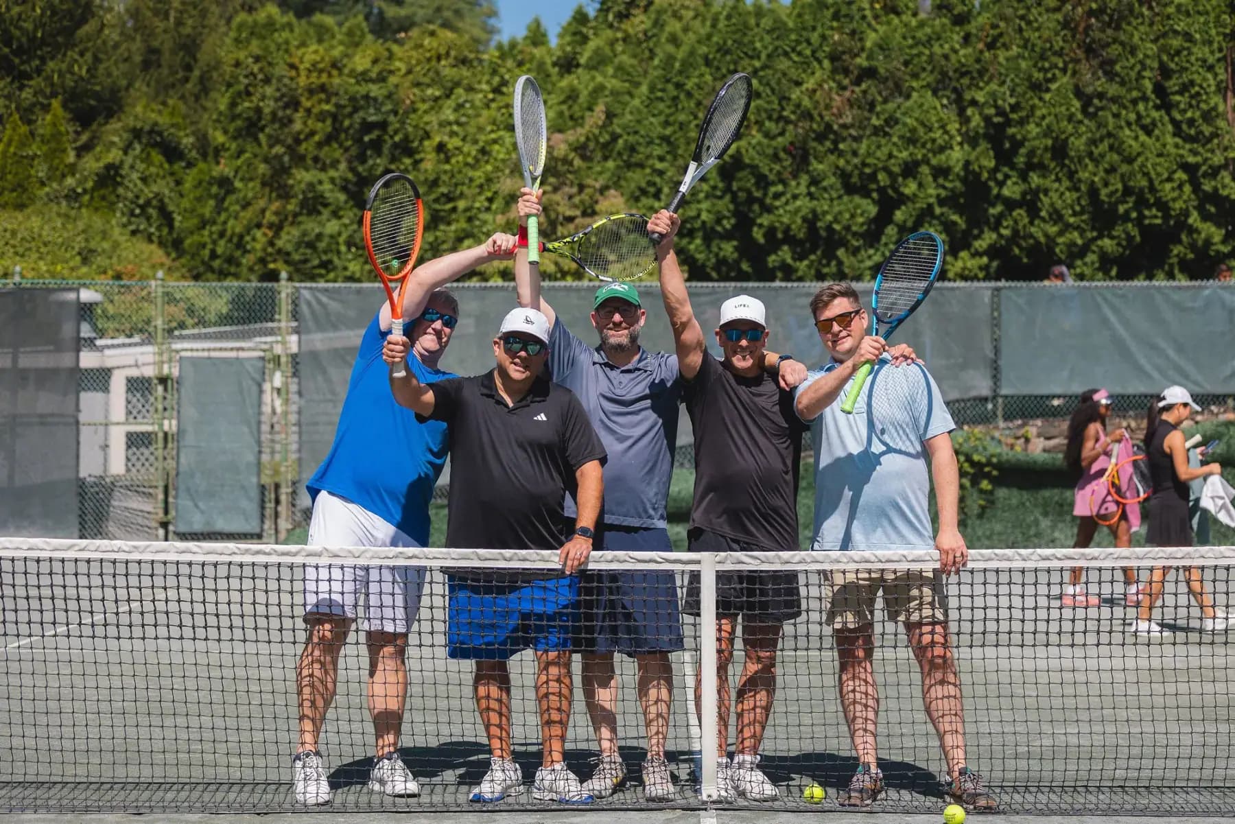 Five men raising rackets behind the net on a court