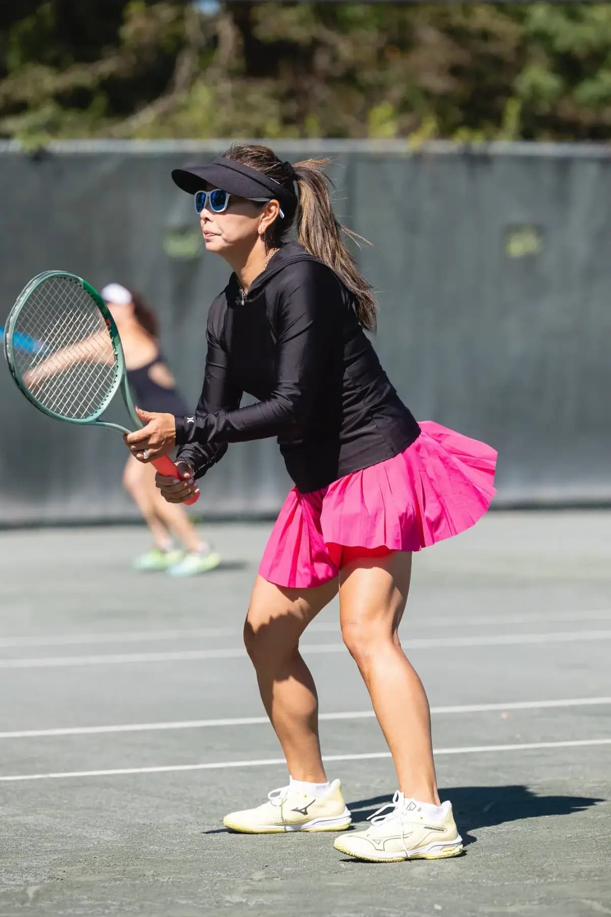Player in a black top and pink skirt ready to hit a ball