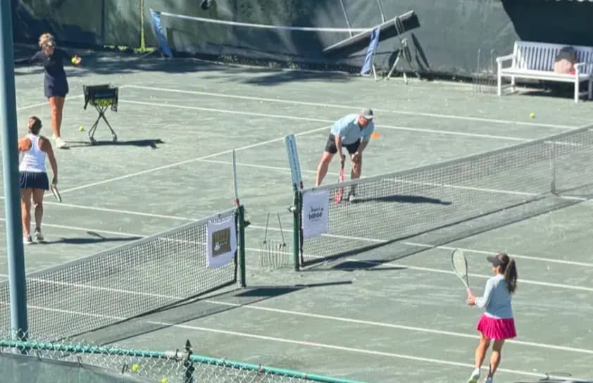 Doubles match on a hard court seen from behind the fence